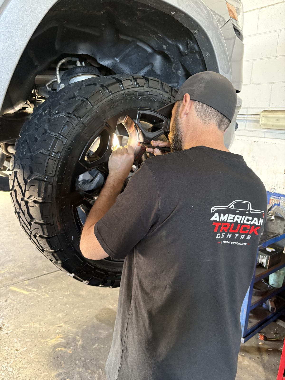 Technician in American Truck Centre uniform checking brakes and wheel hardware